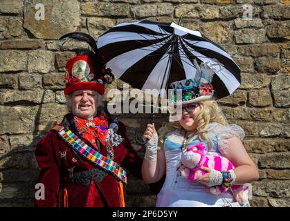 Porträt eines Steampunk-Paares in Alice-im-Wunderland-Kleidung. Die Frau hält einen Sonnenschirm in der Hand. Stockfoto