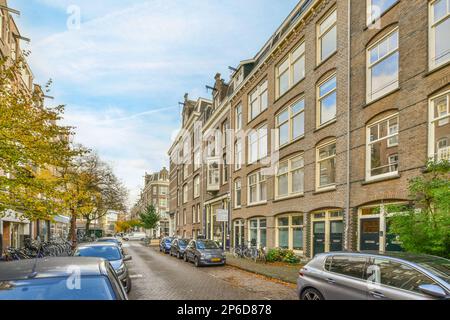 Eine Stadtstraße mit Autos, die an der Seite geparkt sind, und Gebäuden im Hintergrund, aus einem niedrigen Blickwinkel betrachtet Stockfoto