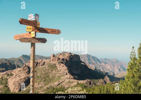 Ein hölzernes Schild für Reisende auf einer wilden vulkanischen Landschaft mit Pinien, Klippen und Felsformationen in Pico de las Nieves, Tejeda, Gran Canaria Stockfoto