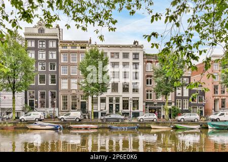 Einige Boote parkten auf dem Wasser vor mehreren Gebäuden und Bäumen, wobei ein Boot auf der anderen Seite angedockt war Stockfoto