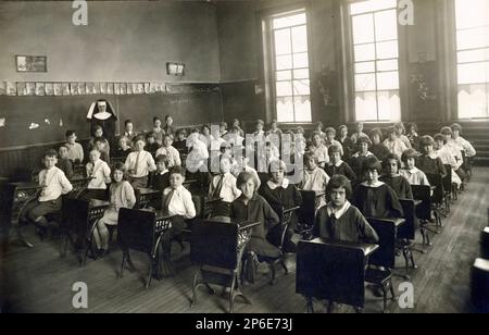 Alte katholische Schule Klassenzimmer Innenausstattung, Kinder sitzen an Schreibtischen mit Händen hinter dem Rücken, Nun in Gewohnheit, Religionsschule, 1930 Stockfoto