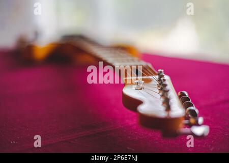 Eine Nahaufnahme der Details auf einer elektrischen Gitarre auf einer pinkfarbenen Oberfläche Stockfoto