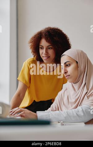 Multiethnische junge weibliche Kollegen, die zusammen an einem Laptop arbeiten. Stockfoto