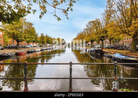Amsterdam, Niederlande - 10. April 2021: Ein Kanal mit Booten im Wasser und Herbstblättern auf den Bäumen entlang der Wasserstraße, amsterdam, niederlande Stockfoto Stockfoto