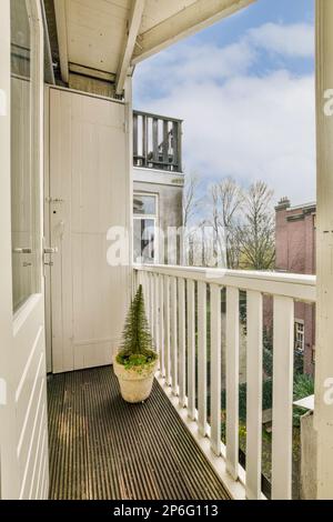 Ein Balkon mit Holzfußboden und weißen Geländern an der Seite des Hauses mit Blick auf die Straße Stockfoto