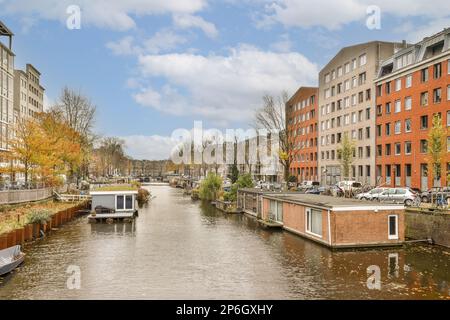 Einige Gebäude und Boote auf dem Wasser in einer städtischen Gegend, die aussieht, als ob sie durch einen Kanal fahren Stockfoto