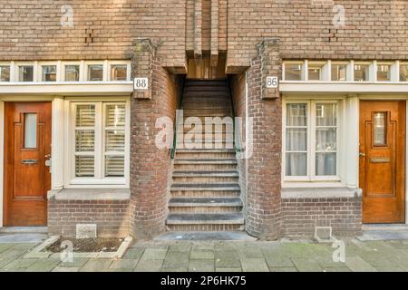 Amsterdam, Niederlande - 10. April 2021: Ein altes Backsteingebäude mit zwei Türen und Stufen bis zur Eingangstür. Dort steht ein Schild mit der Aufschrift „Nein“ Stockfoto