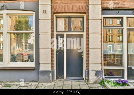 Eine Tür und ein Fenster vor einem Ziegelgebäude mit Fensterläden auf beiden Seiten, die Fenster sind geschlossen Stockfoto