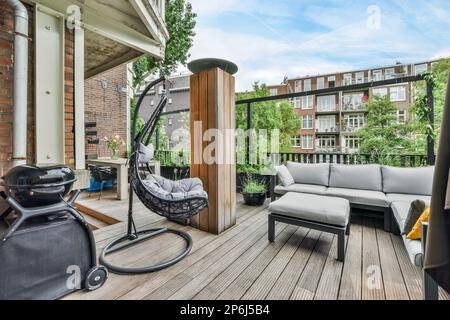 Amsterdam, Niederlande - 10. April 2021: Ein Wohnbereich im Freien mit einem Schaukelstuhl, Sofa und Couchtisch auf der hinteren Terrasse vor einem Ziegelgebäude Stockfoto