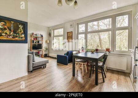 Ein Wohnzimmer mit Holzfußboden und weißen Wänden, einschließlich eines großen Gemäldes an der Wand über dem Esstisch Stockfoto