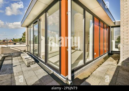 Ein orangefarbenes und weißes Gebäude mit Glastüren außen, im Hintergrund nach oben zum Himmel gerichtet Stockfoto