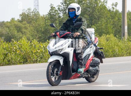 BANGKOK, THAILAND, FEBRUAR 07 2023, Ein Mann in Tarnkleidung fährt ein Motorrad Stockfoto