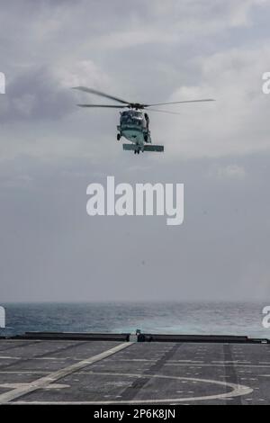 NATUNA SEA (26. Februar 2023) ein MH-60R SeaHawk, angeschlossen an Helicopter Maritime Strike Squadron (HSM) 35, startet vom Cockpit an Bord eines Küstenschiffes der Independence-Klasse USS Oakland (LCS 24), während das Schiff über das Natuna-Meer segelt, am 26. Februar 2023. Oakland, Teil des Destroyer-Geschwaders 7, befindet sich in einem Rotationseinsatz und operiert im US-Flottengebiet 7., um die Interoperabilität mit Alliierten und Partnern zu verbessern und als einsatzbereite Eingreiftruppe zur Unterstützung einer freien und offenen Region Indo-Pazifik zu dienen. (USA Marinefoto von Mass Communication Specialist 2. Class Sang Kim) Stockfoto