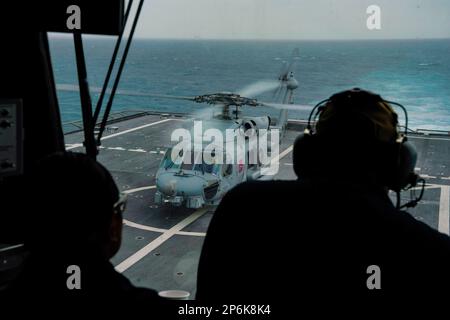 NATUNA SEA (26. Februar 2023) ein MH-60R SeaHawk, angeschlossen an Helicopter Maritime Strike Squadron (HSM) 35, bereitet sich auf den Start vom Cockpit des Küstenschiffes USS Oakland der Unabhängigkeitsklasse (LCS 24) während des Flugbetriebs vor, während das Schiff über die Natuna-See fährt, 26. Februar 2023. Oakland, Teil des Destroyer-Geschwaders 7, befindet sich in einem Rotationseinsatz und operiert im US-Flottengebiet 7., um die Interoperabilität mit Alliierten und Partnern zu verbessern und als einsatzbereite Eingreiftruppe zur Unterstützung einer freien und offenen Region Indo-Pazifik zu dienen. (USA Marinefoto von Mass Communication Specialis Stockfoto