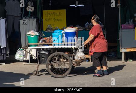 SAMUT PRAKAN, THAILAND, FEBRUAR 13 2023, Eine Frau schiebt einen Wagen mit Eimern auf dem Marktplatz Stockfoto