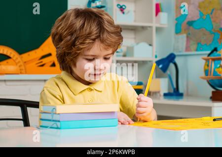 Kinderheimkunde und Heimunterricht. Der Junge macht sich für die Schule fertig. Zurück in die Schule. Glückliche lächelnde Schülerin, die am Schreibtisch malte. Stockfoto
