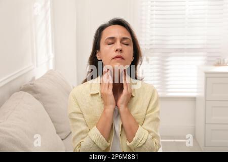 Reife Frau, die zu Hause eine Schilddrüsen-Selbstuntersuchung macht Stockfoto