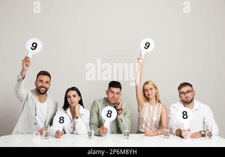 Jury mit unterschiedlichen Punktezeichen am Tisch auf beigefarbenem Hintergrund Stockfoto