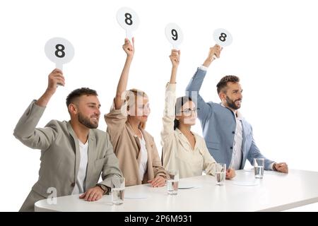 Jury-Gruppe mit unterschiedlichen Punktezeichen am Tisch auf weißem Hintergrund Stockfoto