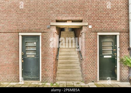 Ein altes Backsteingebäude mit zwei Türen und Stufen, die zum Eingang führen Stockfoto