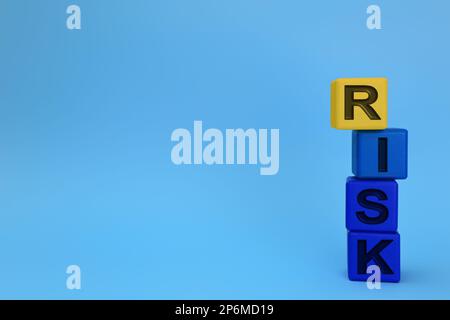 Stapel farbiger Holzwürfel mit Wortrisiko auf hellblauem Hintergrund. Platz für Text Stockfoto