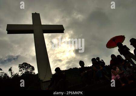 Silhouette von Besuchern und ein hohes christliches Kreuz im Bukit Kasih (Hügel der Liebe), einem beliebten religiösen Reiseziel im Dorf Kanonang, West Kawangkoan, Minahasa, North Sulawesi, Indonesien. Gewidmet allen religiösen Gläubigen und Gläubigen, während sie die Geister der Liebe, des Friedens und der Toleranz fördern; Bukit Kasih wurde Anfang 2000 gegründet, als Adolf J. Sondakh Gouverneur der Provinz Nord-Sulawesi war. Sie wurde als noble Friedensinitiative betrachtet; eine Reaktion auf Konflikte auf Grund der Religion und der ethnischen Zugehörigkeit geschah vor und um 2000 in mehreren anderen Provinzen. Stockfoto