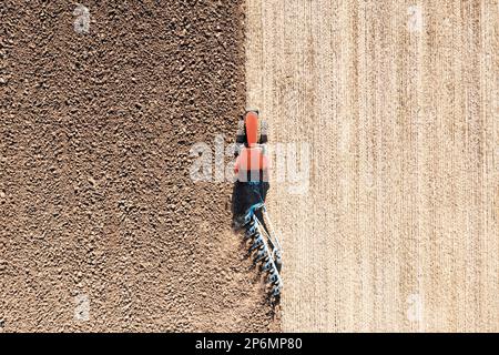 Traktor zieht den Pflug auf dem landwirtschaftlichen Feld an sonnigen Tagen, Luftaufnahme Stockfoto