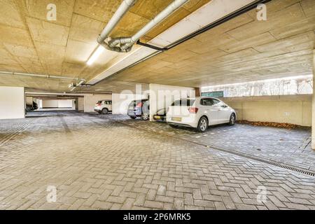 Zwei Autos, die auf einem leeren Parkplatz geparkt sind, ohne dass jemand auf dem Boden ist, und es gibt ein weiteres Auto, das entfernt wurde Stockfoto