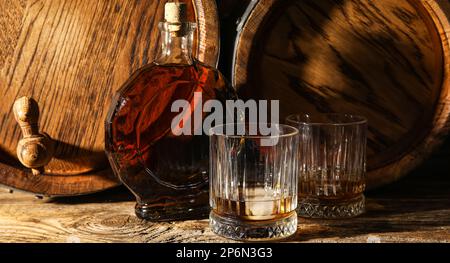 Flasche Whiskey, Gläser und Fässer im Keller Stockfoto