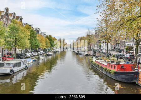 Einige Boote im Wasser und Gebäude auf beiden Seiten des Kanals mit Bäumen, die beide Seiten säumen Stockfoto