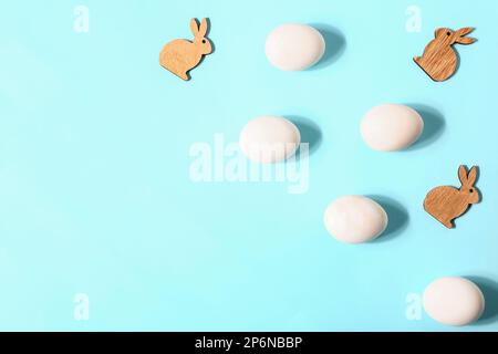 Natürliche Ostereier und Hasenfiguren aus Holz auf farbigem Hintergrund Stockfoto
