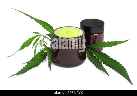 Gläser mit Hanfcreme und grünen Blättern auf weißem Hintergrund. Natürliche Kosmetik Stockfoto