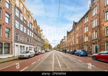 Eine leere Straße mit seitlich geparkten Autos und Gebäuden im Hintergrund, aus der Perspektive des Autos Stockfoto