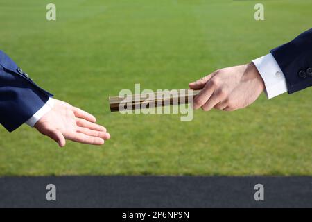 Geschäftsmann, der seinen Partner draußen mit Stab versorgt, Nahaufnahme Stockfoto