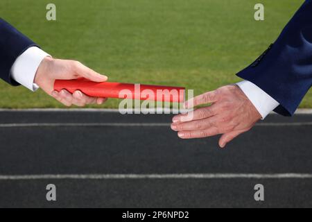 Geschäftsmann, der seinen Partner draußen mit Stab versorgt, Nahaufnahme Stockfoto