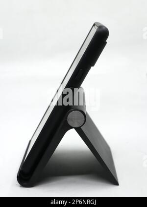 Ein Smartphone, das in einem Winkel, isoliert auf weißem Hintergrund, auf einem verstellbaren mobilen Ständer platziert wird Stockfoto