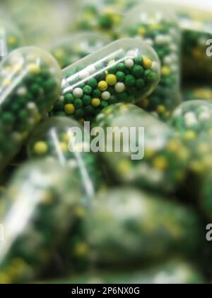 Nahaufnahme von Speisekapseln mit Pillen in grüner, gelber und weißer Farbe, die Vitamine und Mineralien als Nahrungsergänzungsmittel enthalten Stockfoto