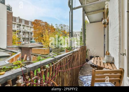 Ein Außenbereich mit Möbeln und Pflanzen auf dem Balkon, von innen gesehen mit Blick auf den Hof darunter, ist ein blauer Himmel Stockfoto