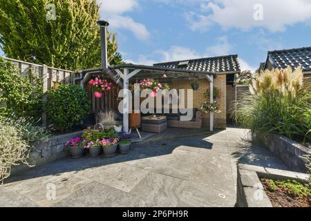 Amsterdam, Niederlande - 10. April 2021: Eine Terrasse mit Topfpflanzen und Blumen auf dem Betongang, der zu einem Küchenbereich im Garten führt Stockfoto