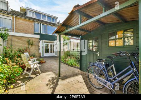 Amsterdam, Niederlande - 10. April 2021: Ein Fahrrad vor einem Haus mit Pflanzen und Blumen auf der Seite des Hauses daneben Stockfoto