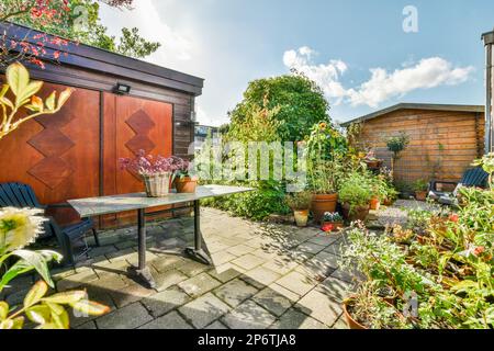 Amsterdam, Niederlande - 10. April 2021: Ein Außenbereich mit einigen Pflanzen und Töpfen auf dem Boden vor einem eingezäunten Holzschuppen Stockfoto