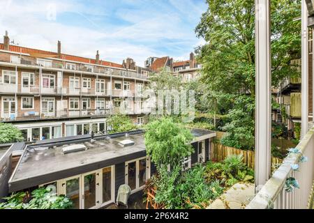 Amsterdam, Niederlande - 10. April 2021: Ein Balkon mit vielen Pflanzen und Gebäuden im Hintergrund aus dem oberen Fenster eines Apartments Stockfoto