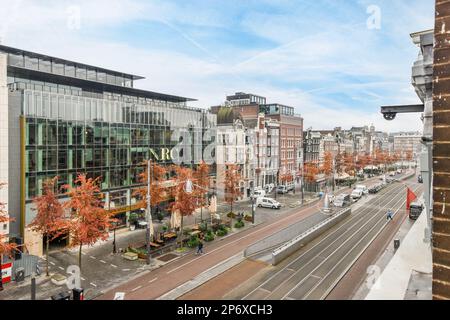 Amsterdam, Niederlande - 10. April 2021: Eine Stadtstraße mit Gebäuden und Bäumen im Vordergrund - aufgenommen von einem überfahrenen Busfenster Stockfoto