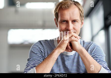 Unternehmer machen es möglich. Porträt eines lächelnden Mannes, der in einer zwanglosen Arbeitsumgebung sitzt. Stockfoto