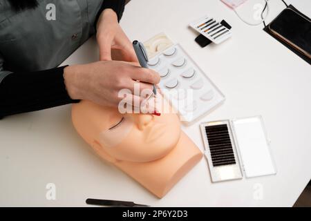 Grundausbildung, Wimpern an einer Schaufensterpuppe aus Silikon zu bauen. Wimpernverlängerung. Der Master-Marker legt die Führungslaschen des Kennzeichnungsschemas an. Stockfoto