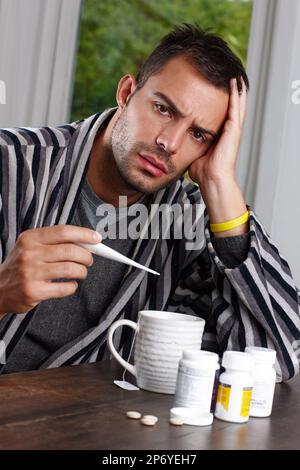 Sieht aus, als müsste ich mich heute krank melden. Ein unglücklicher Mann, der seine Temperatur auf einem Thermometer zu Hause ableste. Stockfoto