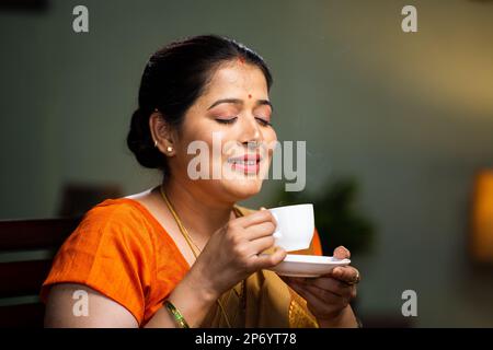 Entspannte Frau, die zu Hause am Morgen Tee oder Kaffee trinkt - Konzept von Ruhe, Ruhe und Wohlbefinden Stockfoto