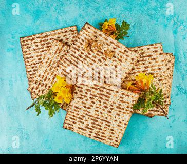 Pesach-Festungskonzept - jüdischer Feiertag Pesach. Matzo mit Blumen und Nüssen auf blauem Hintergrund. Blick von oben. Flach verlegt Stockfoto