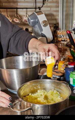 Der Koch knackt ein Ei in ein Gericht, das in einer Schüssel zubereitet wird Stockfoto