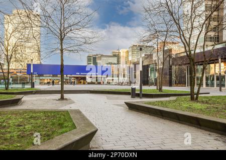 Ein Stadtplatz mit Bänken und Bäumen im Vordergrund - das Bild wurde aus einer tatsächlichen Zeitrunde auf diesem Foto aufgenommen Stockfoto